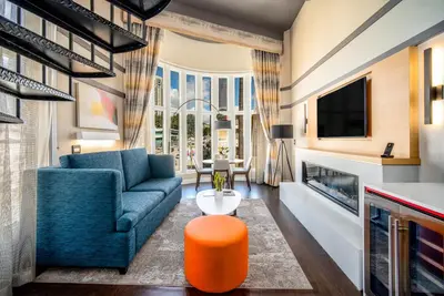 a living room with a blue couch and an orange stool at Century Park Hotel LA in Los Angeles