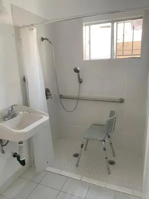a bathroom with a sink and a chair in a shower at Encore Inn Inglewood in Inglewood