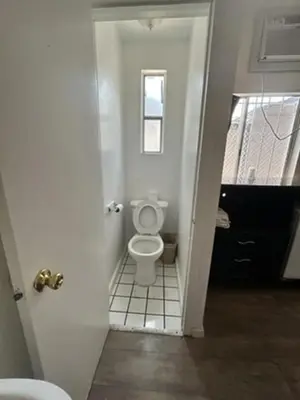 a white bathroom with a toilet in a hallway at Encore Inn Inglewood in Inglewood
