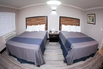 a hotel room with two beds and a desk at Diamond Bell Inn & Suites in Bell