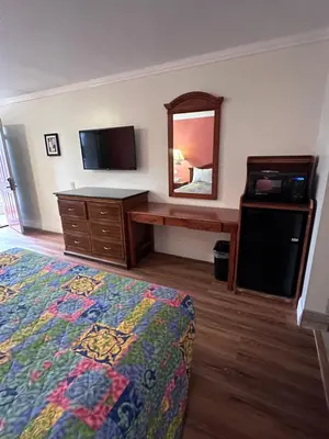 a bedroom with a bed and a dresser and a mirror at Willow Tree Lodge in Fullerton