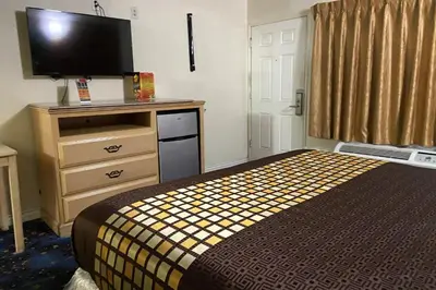 a hotel room with a bed and a flat screen tv at Robinhood Motel Anaheim West in Anaheim