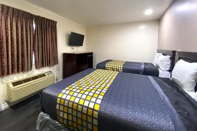 a hotel room with two beds and a tv at Robinhood Motel Anaheim West in Anaheim