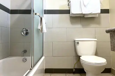 a small bathroom with a toilet and a shower at Robinhood Motel Anaheim West in Anaheim