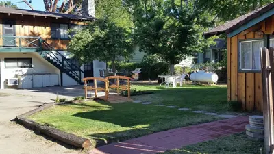 a yard with a wooden bench in the grass at Kern Riverfront Lodge in Kernville