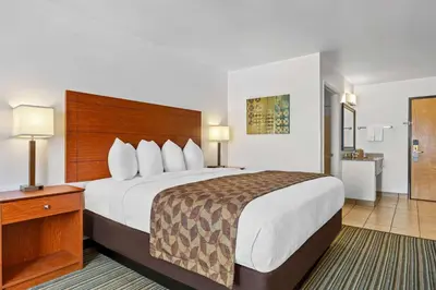 a hotel room with a large bed and a bathroom at Best Western Liberty Inn in Delano