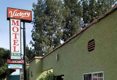 a building with a neon sign next to a building at Victory Motel Inn near Universal & Hollywood in Glendale