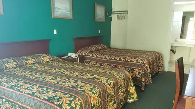 two beds in a hotel room with green walls at Victory Motel Inn near Universal & Hollywood in Glendale