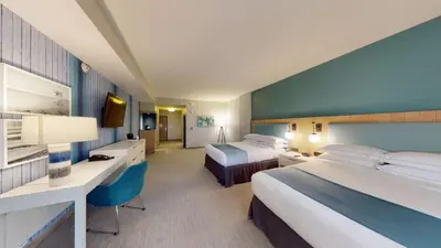 a hotel room with two beds and a desk at SunCoast Hotel Anaheim, Tapestry Collection by Hilton in Anaheim