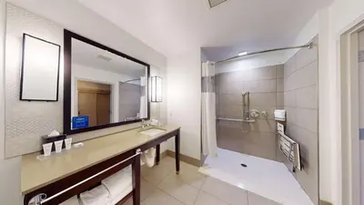 a bathroom with a large mirror and a shower at SunCoast Hotel Anaheim, Tapestry Collection by Hilton in Anaheim