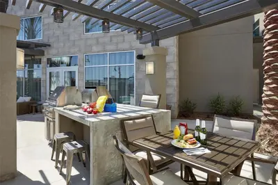 a patio with a table and chairs and an outdoor kitchen at Homewood Suites By Hilton Los Angeles Redondo Beach in Redondo Beach