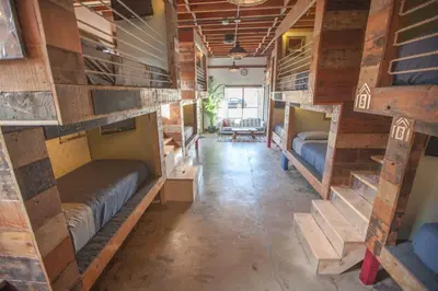 a room with several bunk beds and a room with a table at PodShare East Hollywood in Los Angeles