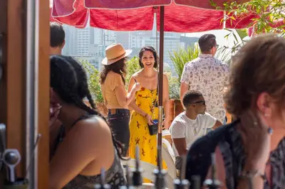 a woman in a yellow dress and hat standing under an umbrella at Freehand Los Angeles in Los Angeles