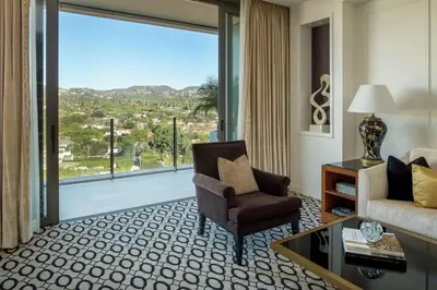 a living room with a couch and a chair and a large window at Waldorf Astoria Beverly Hills in Los Angeles