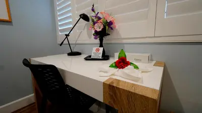 a desk with a lamp and a vase of flowers on it at El Royale Gardens Near Universal Studios in Los Angeles