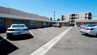 a parking lot with cars parked in front of a building at El Royale Gardens Near Universal Studios in Los Angeles