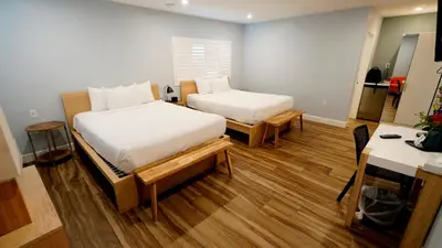 a bedroom with two beds and a table and a desk at El Royale Gardens Near Universal Studios in Los Angeles