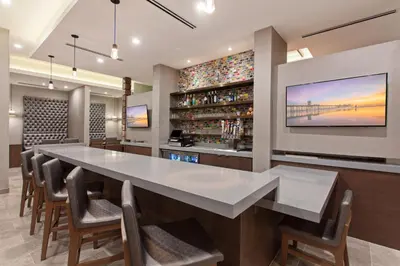 a bar with a large white table and chairs at SpringHill Suites by Marriott Huntington Beach Orange County in Huntington Beach