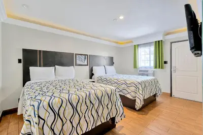 a hotel room with two beds and a flat screen tv at Mid City Inn in Los Angeles