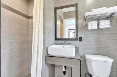 a bathroom with a sink and a toilet and a mirror at Mid City Inn in Los Angeles