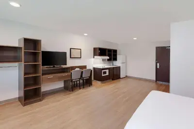 a room with a bed and a desk with a television at WoodSpring Suites Bakersfield East in Bakersfield