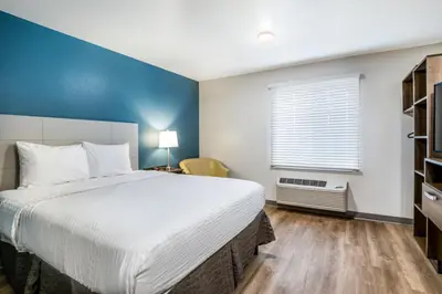 a bedroom with a large bed and a blue wall at WoodSpring Suites Bakersfield East in Bakersfield