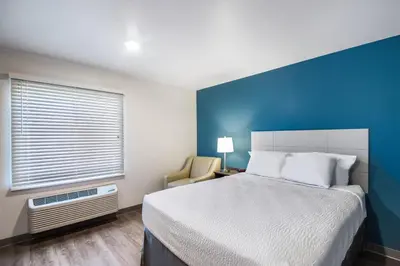 a bedroom with a bed and a blue wall at WoodSpring Suites Bakersfield East in Bakersfield