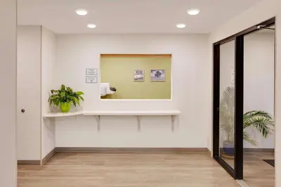 a hallway with a mirror and a potted plant at WoodSpring Suites Bakersfield East in Bakersfield