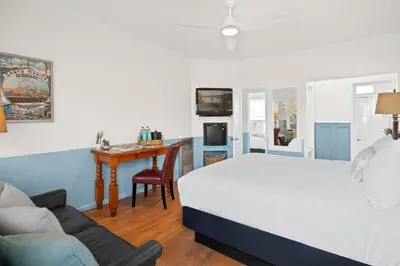a bedroom with a white bed and a desk and a couch at Sea Blue Hotel in Los Angeles
