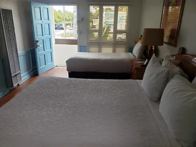 a bedroom with two beds and a door with a window at Sea Blue Hotel in Los Angeles