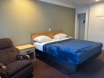a bedroom with a bed and a chair and a chair at Welcome Inn in Los Angeles