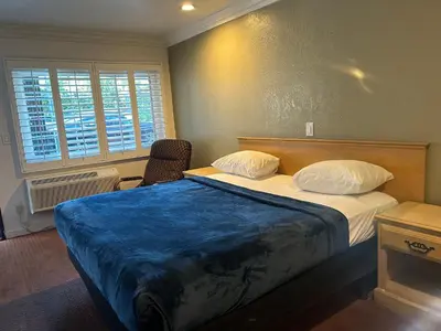 a bedroom with a large bed with a blue blanket on it at Welcome Inn in Los Angeles