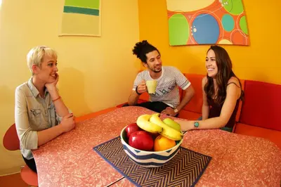 three people sitting around a table with a bowl of fruit at Banana Bungalow Hollywood Hotel & Hostel in Los Angeles