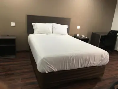 a bedroom with a large bed with white sheets and pillows at Baymont by Wyndham Bakersfield in Bakersfield