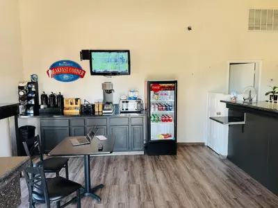a kitchen with a refrigerator and a table and chairs at Baymont by Wyndham Bakersfield in Bakersfield