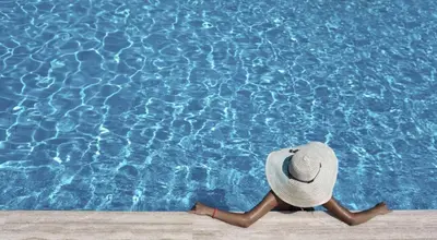 a person in a hat sitting in front of a swimming pool at Courtyard by Marriott Riverside UCR/Moreno Valley Area in Riverside