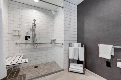 a bathroom with a shower and a toilet and towels at Cambria Hotel LAX in El Segundo