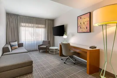 a hotel room with a desk and a couch and a chair at Cambria Hotel LAX in El Segundo