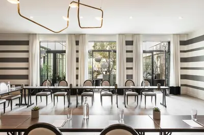 a dining room with tables and chairs and a chandelier at Kimpton La Peer Hotel West Hollywood by IHG in Los Angeles