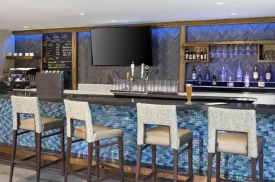 a bar with four chairs and a counter with wine bottles at The Cove Hotel in Long Beach