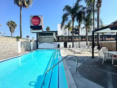 a swimming pool with chairs and a hotel sign and palm trees at The Dixie Hollywood in Los Angeles