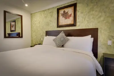 a bedroom with a large white bed and a mirror at Vagabond Inn San Pedro in San Pedro