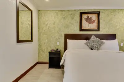a bedroom with a large white bed and a mirror at Vagabond Inn San Pedro in San Pedro
