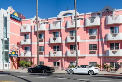 two cars parked in front of a pink building at Days Inn by Wyndham Santa Monica in Los Angeles
