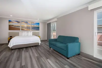 a bedroom with a bed and a blue chair at Days Inn by Wyndham Santa Monica in Los Angeles