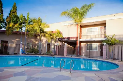 a swimming pool in front of a building with palm trees at Budget Inn Anaheim near Disneyland Drive in Anaheim
