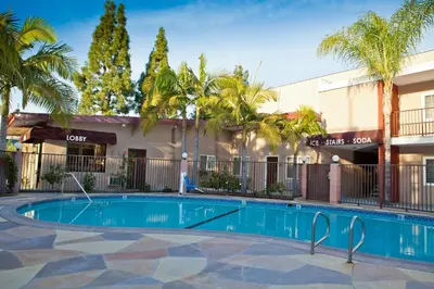 a swimming pool in front of a building with palm trees at Budget Inn Anaheim near Disneyland Drive in Anaheim