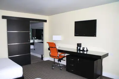 a hotel room with a desk and a bed and a television at Hotel Current in Long Beach