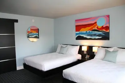 a hotel room with two beds and a painting on the wall at Hotel Current in Long Beach