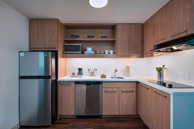 a kitchen with wooden cabinets and a stainless steel refrigerator at Element Palmdale in Palmdale